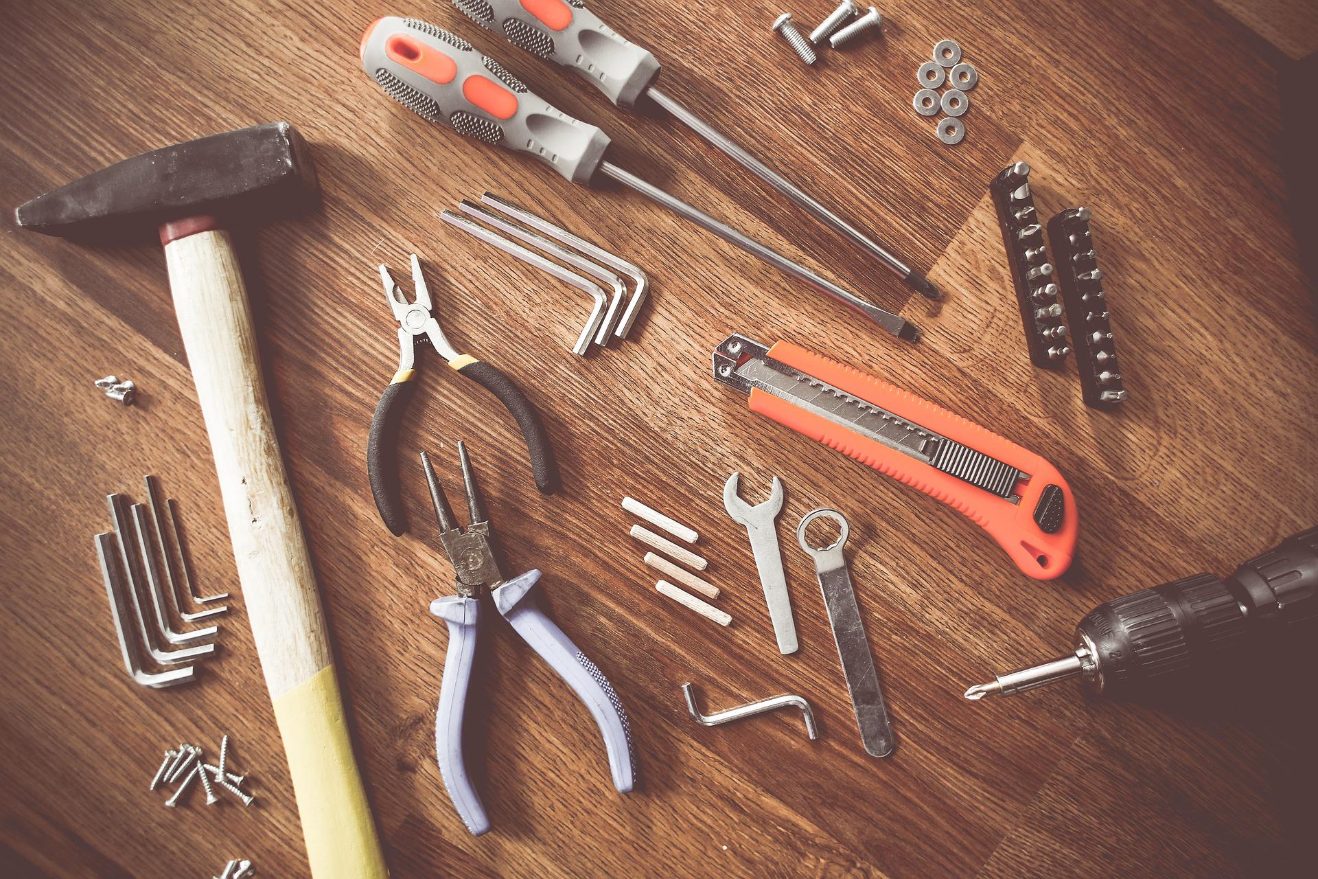 Various tools, including a hammer, pilers, hex keys, screwdrivers and more, on a wooden surface.