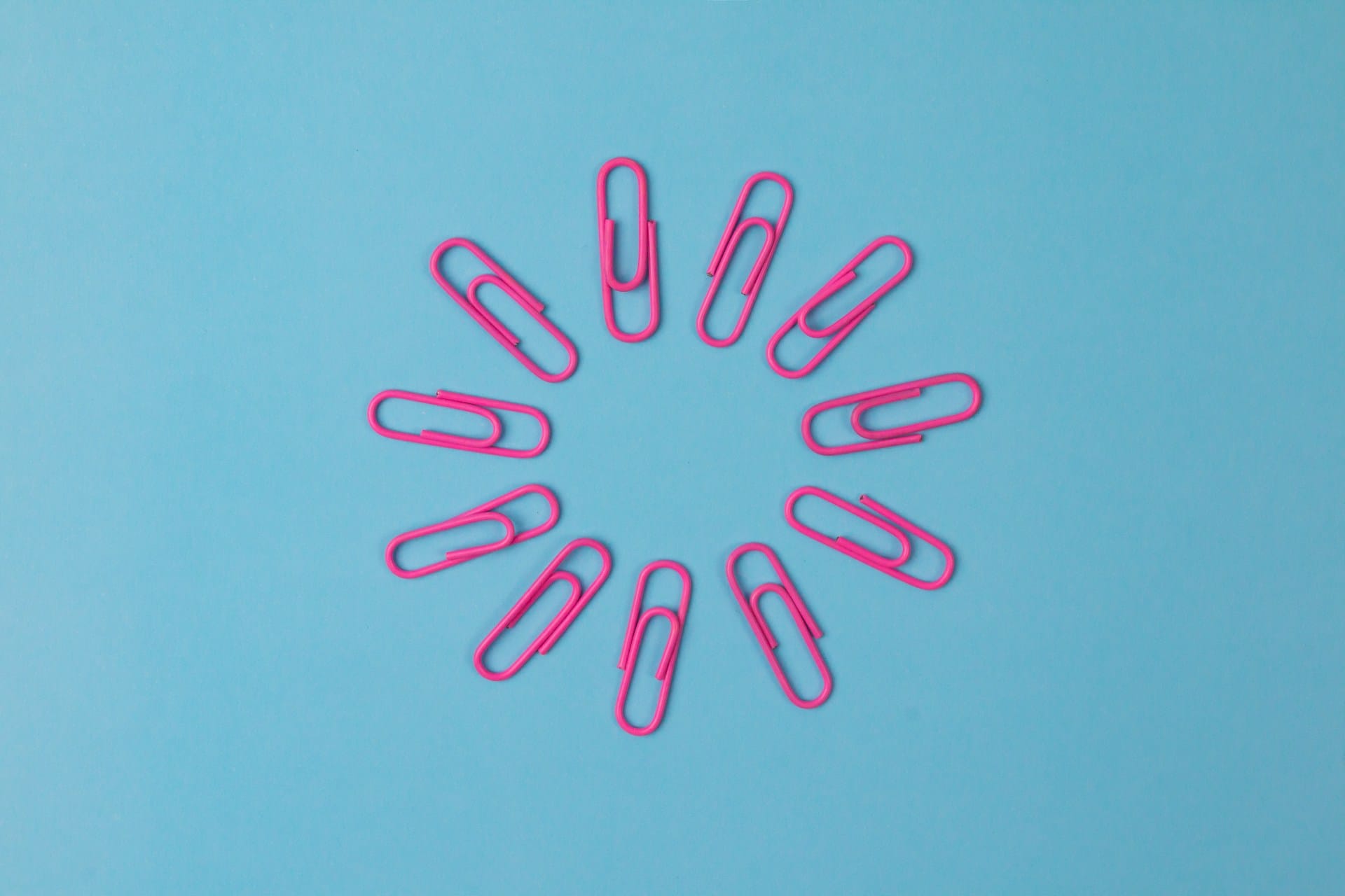 Composition of pink paper clips isolated on blue background